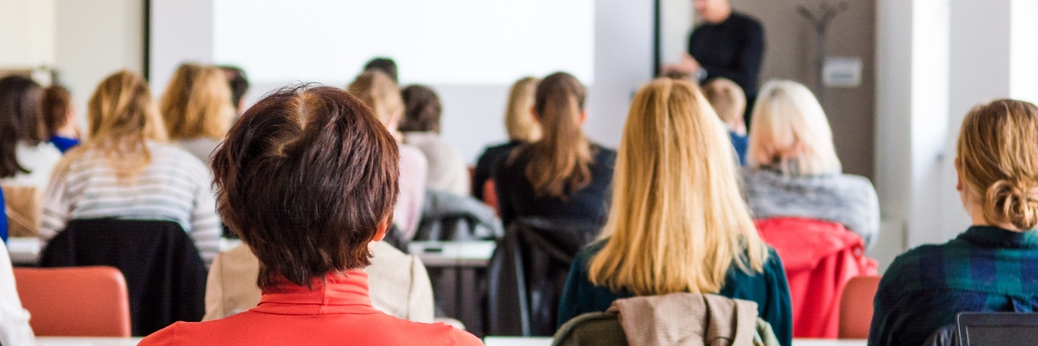 People sitting in a room and looking at someone presenting