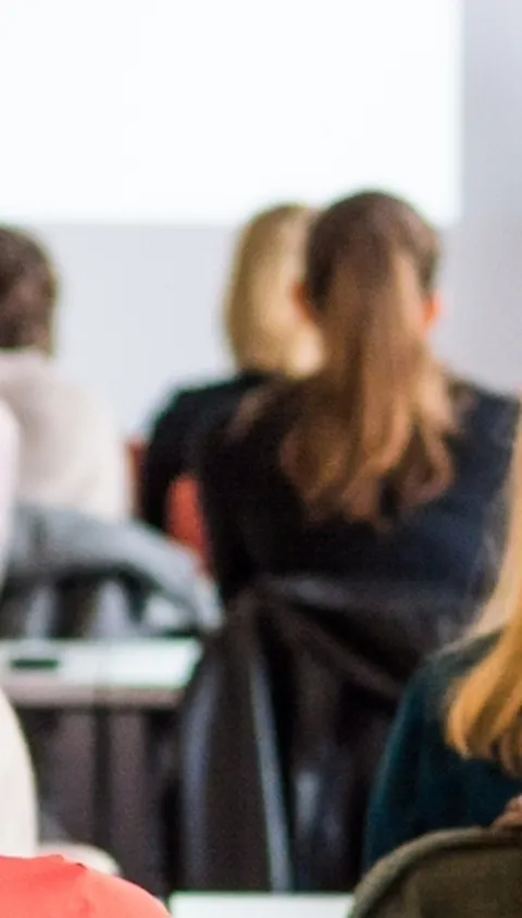People sitting in a room and looking at someone presenting